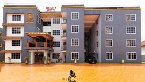A multi-story hotel with a modern design, featuring a prominent entrance with a covered area and a sign that reads "IKE CITY HOTEL". - IKE CITY Hotel (Tema)