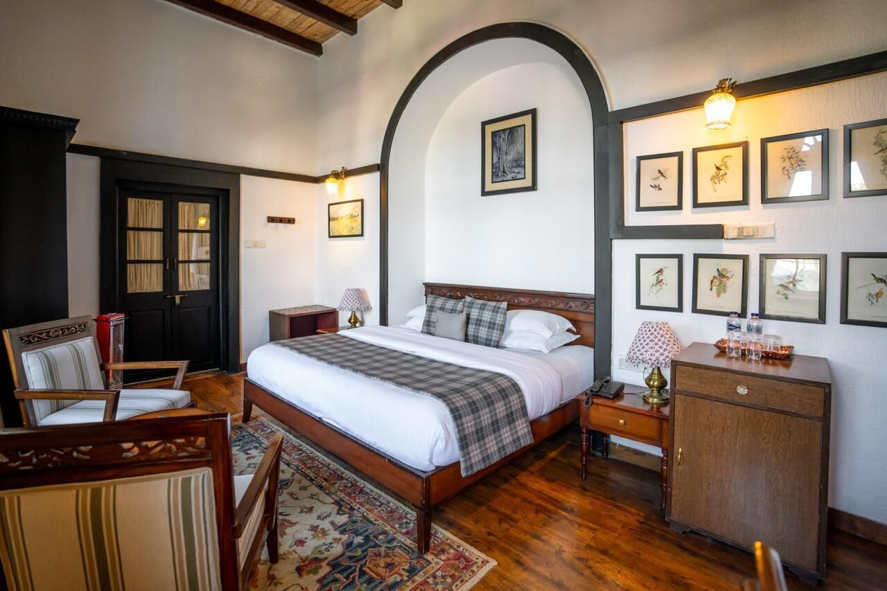 A traditional room with a bed, wooden furniture, and framed artwork on the walls.