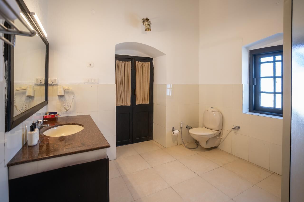 A bathroom with a sink, toilet, and a window.