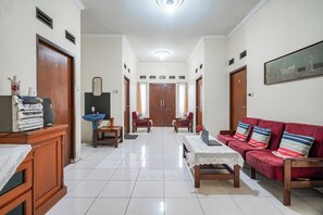 A spacious living room with a red sofa, a wooden cabinet, a blue sink, and a door with the number 7. - OYO 94102 Kuningan Guest House Syariah (Bandung)