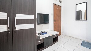 Ein Zimmer mit einem dunklen Holzschrank, einem Fernseher auf einem Schrank und einer Holzschiebetür, sowie einem Spiegel an der Wand.