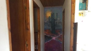 Un pasillo estrecho con un mural en la pared, puertas de madera y suelo de baldosas.