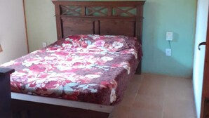 Un dormitorio con cama, cabecera de madera y ventilador de techo.