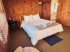 A wooden-paneled room with a bed, a nightstand, and a small desk. - Room 3 • Desert Retreat - Downtown Joshua Tree (Joshua Tree)