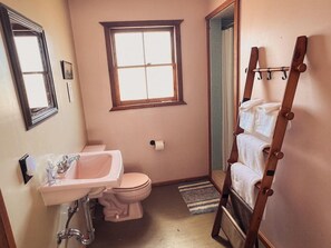 A small, compact bathroom with a toilet, sink, and window. - Room 3 • Desert Retreat - Downtown Joshua Tree (Joshua Tree)