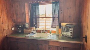 Eine Holzhüttenküche mit Fenster, Spüle, Kaffeemaschine und Radio.