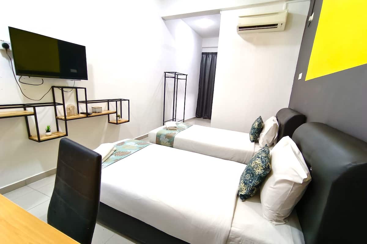 Une chambre d’hôtel avec deux lits, un bureau, une télévision et une fenêtre avec des rideaux.