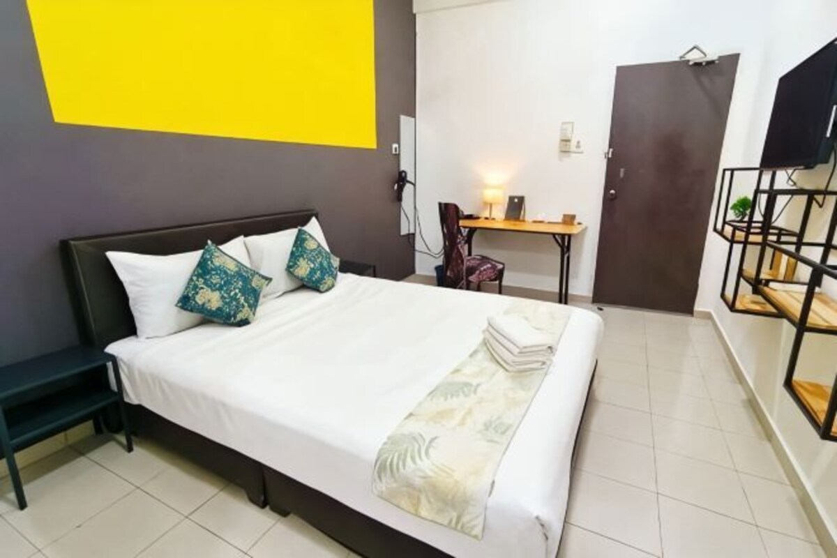 A hotel room with a bed, bedside table, and a desk.