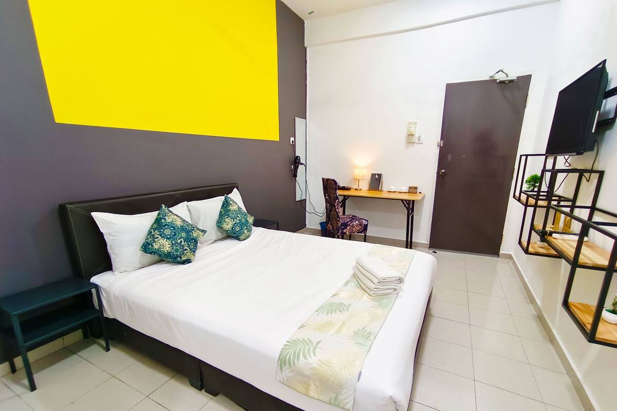 Une chambre d’hôtel comprenant un lit, un bureau, une chaise, une télévision et une armoire.