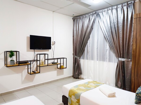 A hotel room with a bed, a TV mounted on the wall, and a window with curtains. - Salaam Suites Hotel (Kota Bharu)