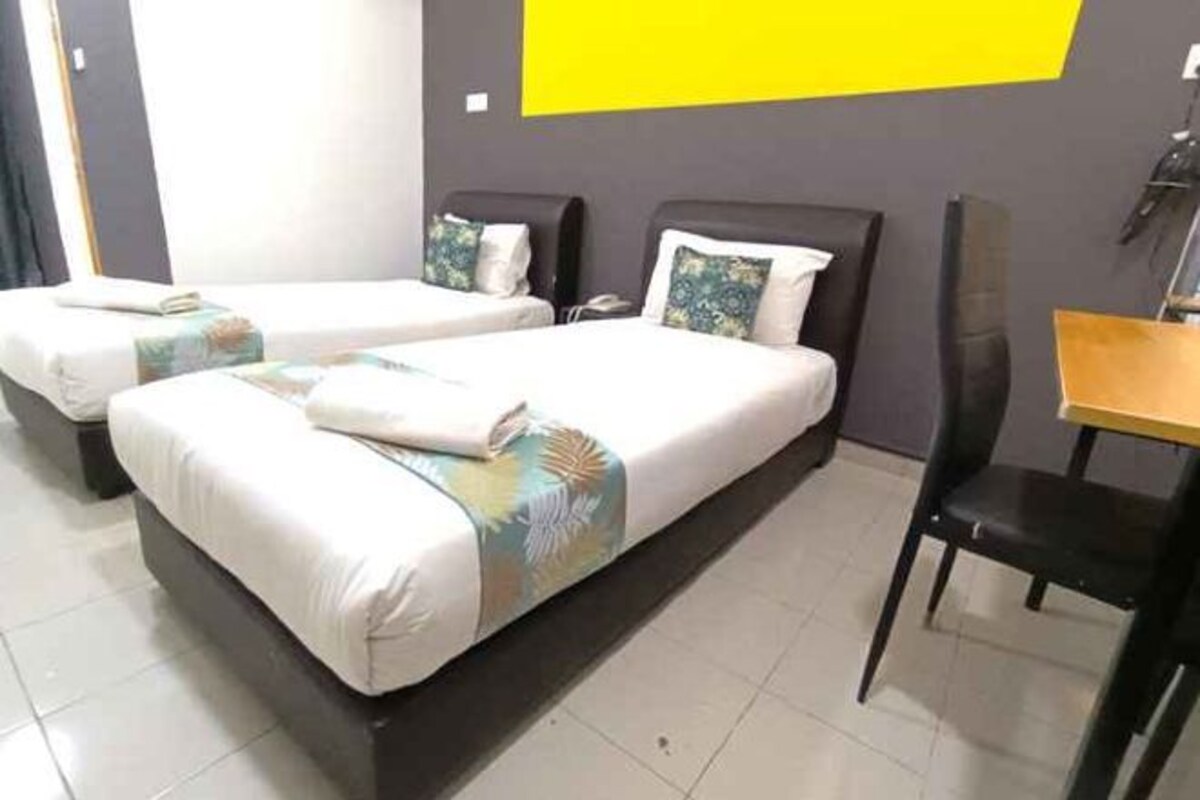 A hotel room with two beds, a desk, and a chair.