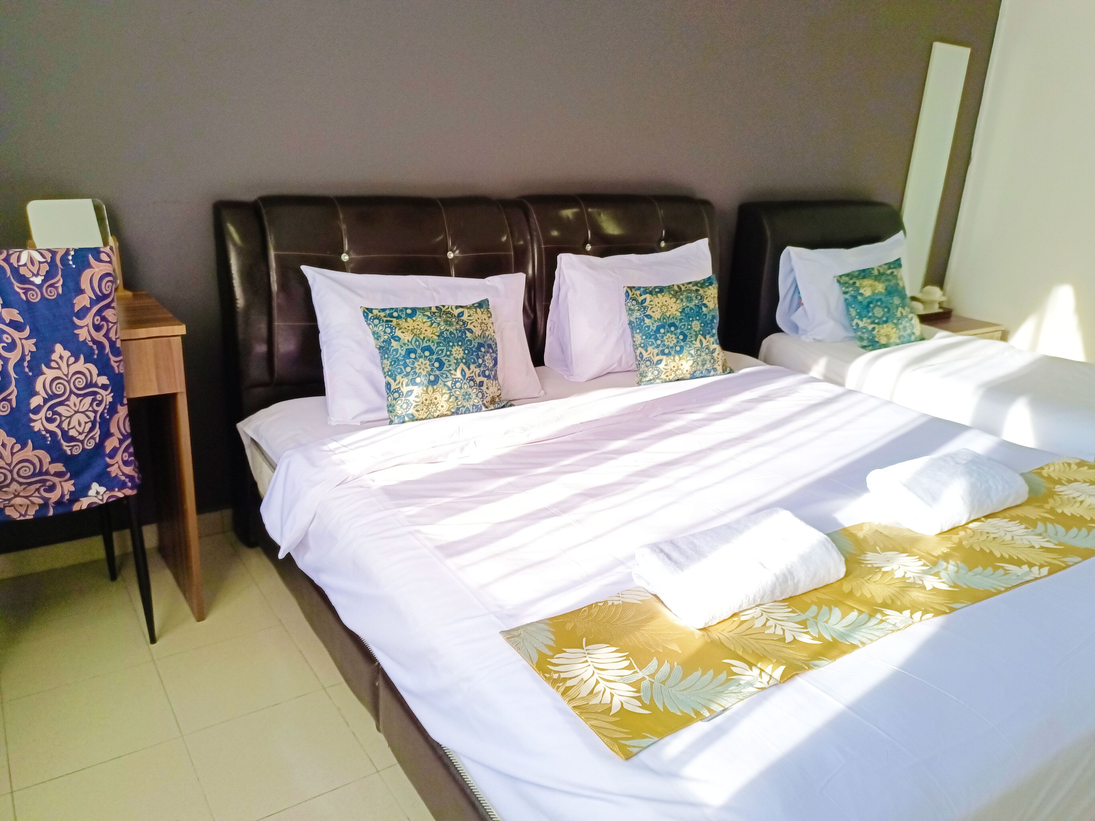 A hotel room with a large bed, two nightstands, a chair, and a mirror.