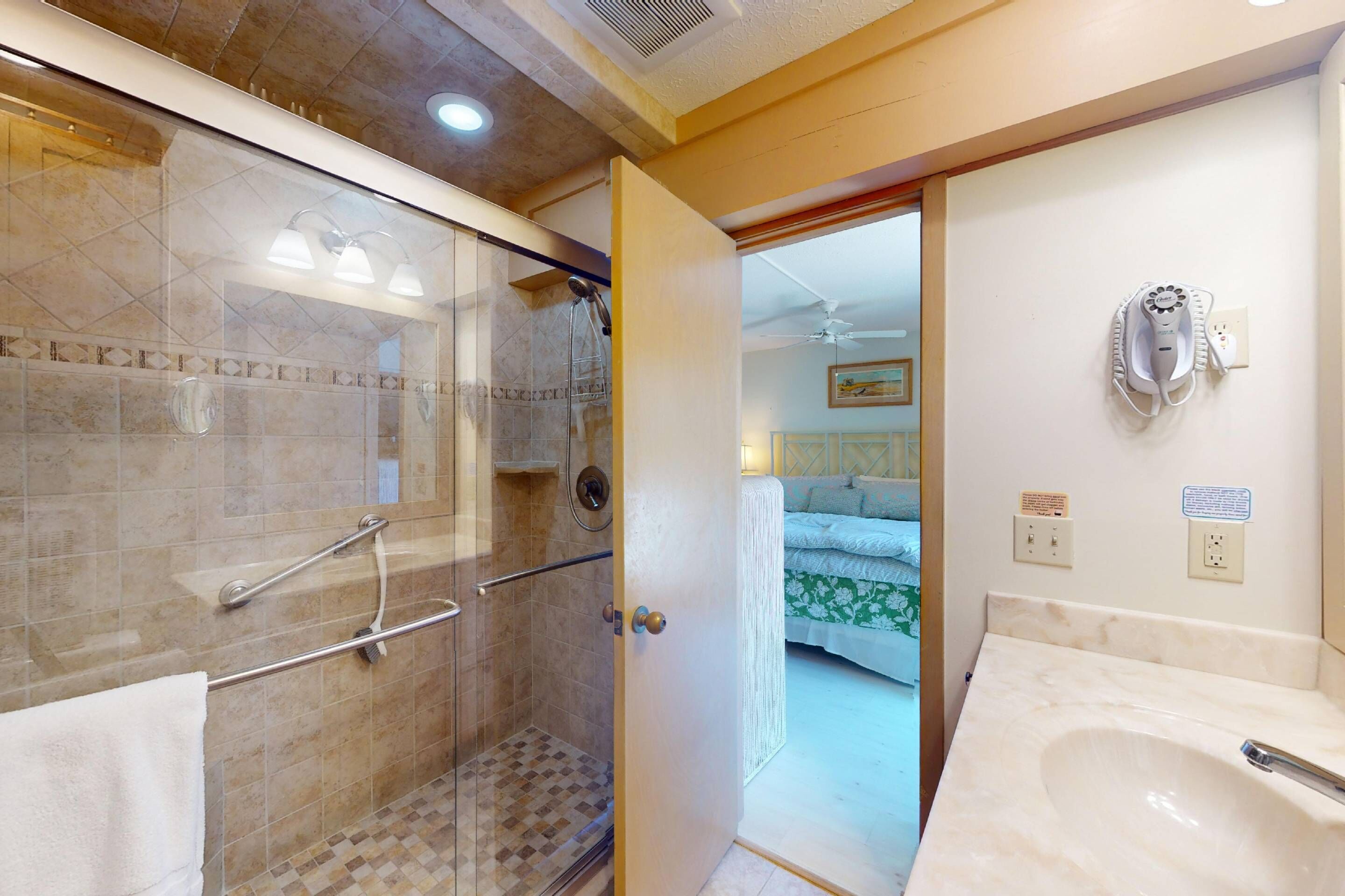 A bathroom with a glass-enclosed shower, a sink, and a toilet.