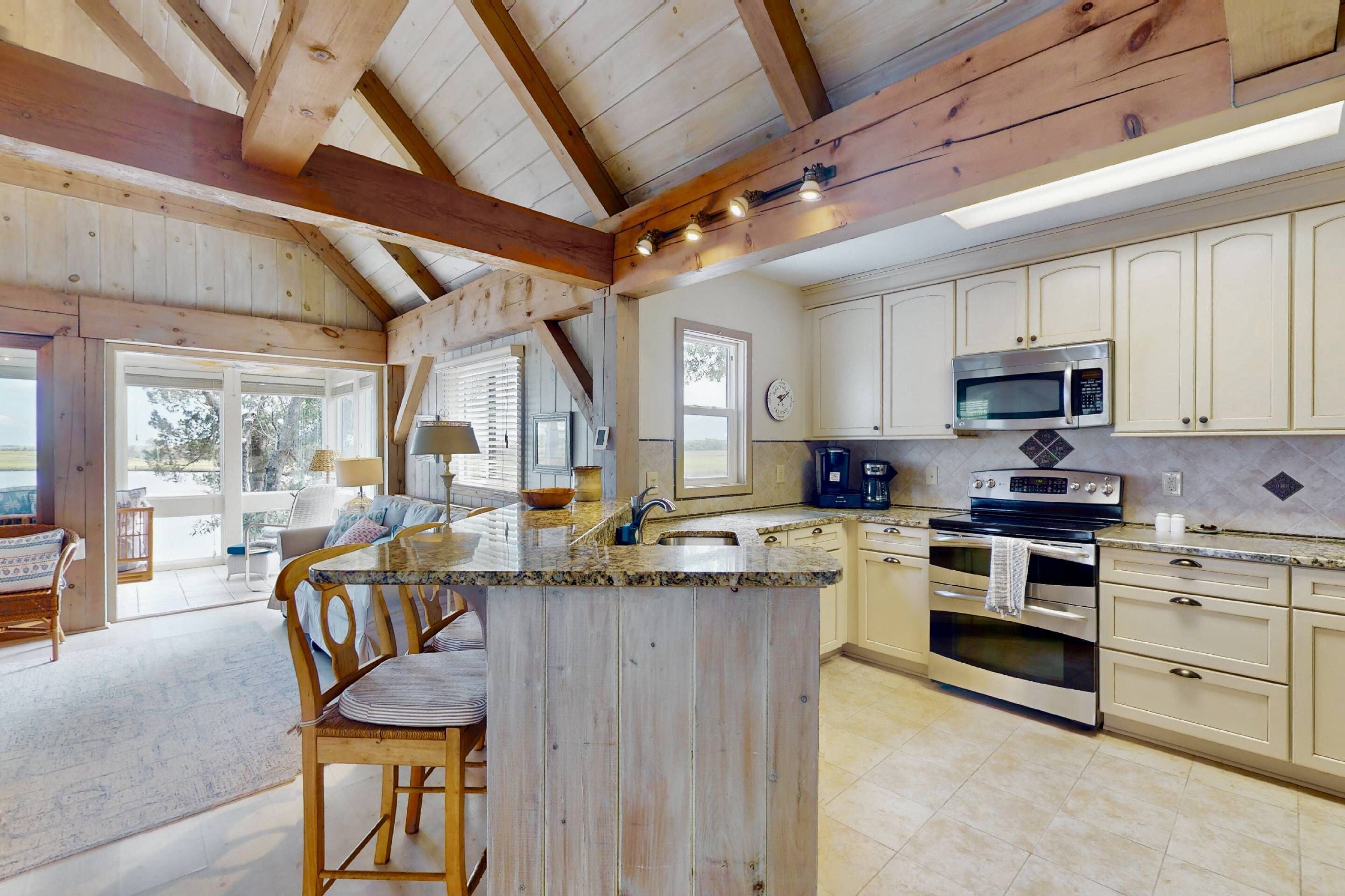 A spacious kitchen with wooden beams, a central island, and modern appliances.