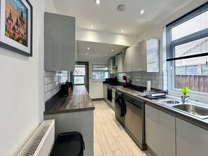 Una cocina moderna con una isla central, electrodomésticos integrados y un ventanal con persianas.