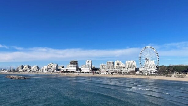 Eine Küstenstadt mit einem markanten Riesenrad und modernen Hochhäusern entlang der Strandpromenade.