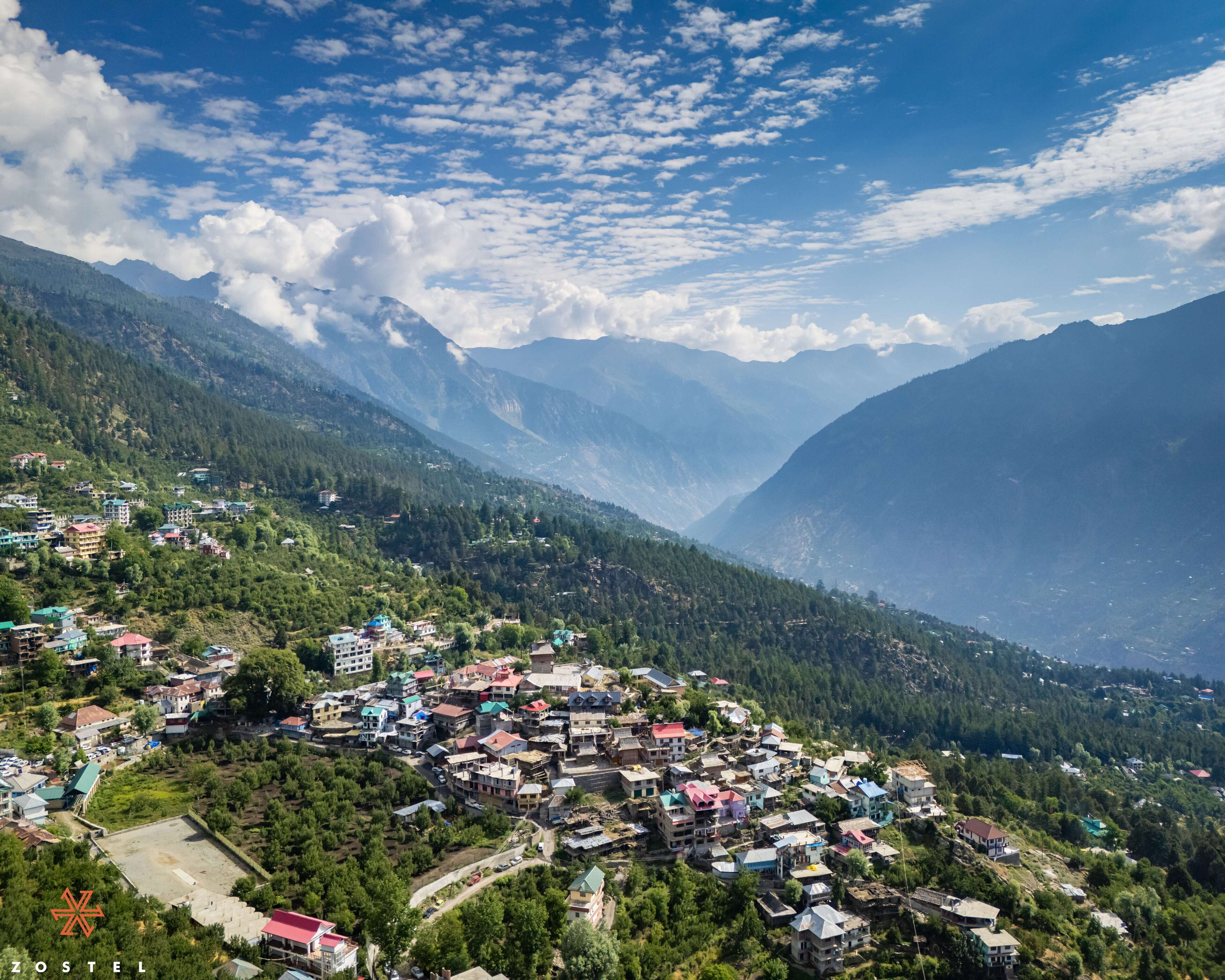 A mountainous town with dense greenery and a variety of buildings, including residential and possibly commercial structures.