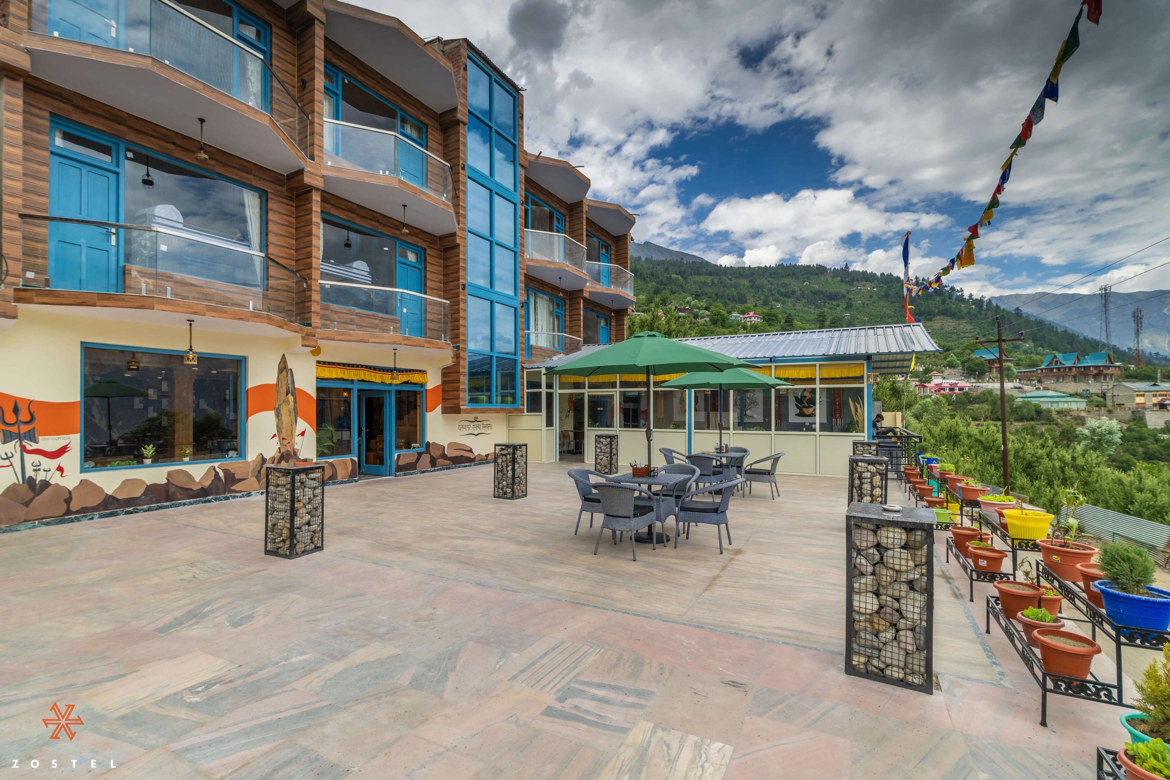 A hotel with a terrace featuring outdoor seating, a mountain view, and traditional decor.
