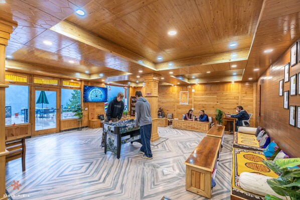 A cozy indoor setting with a foosball table, wooden walls, and a patterned floor. - Zostel Kalpa (Kalpa)