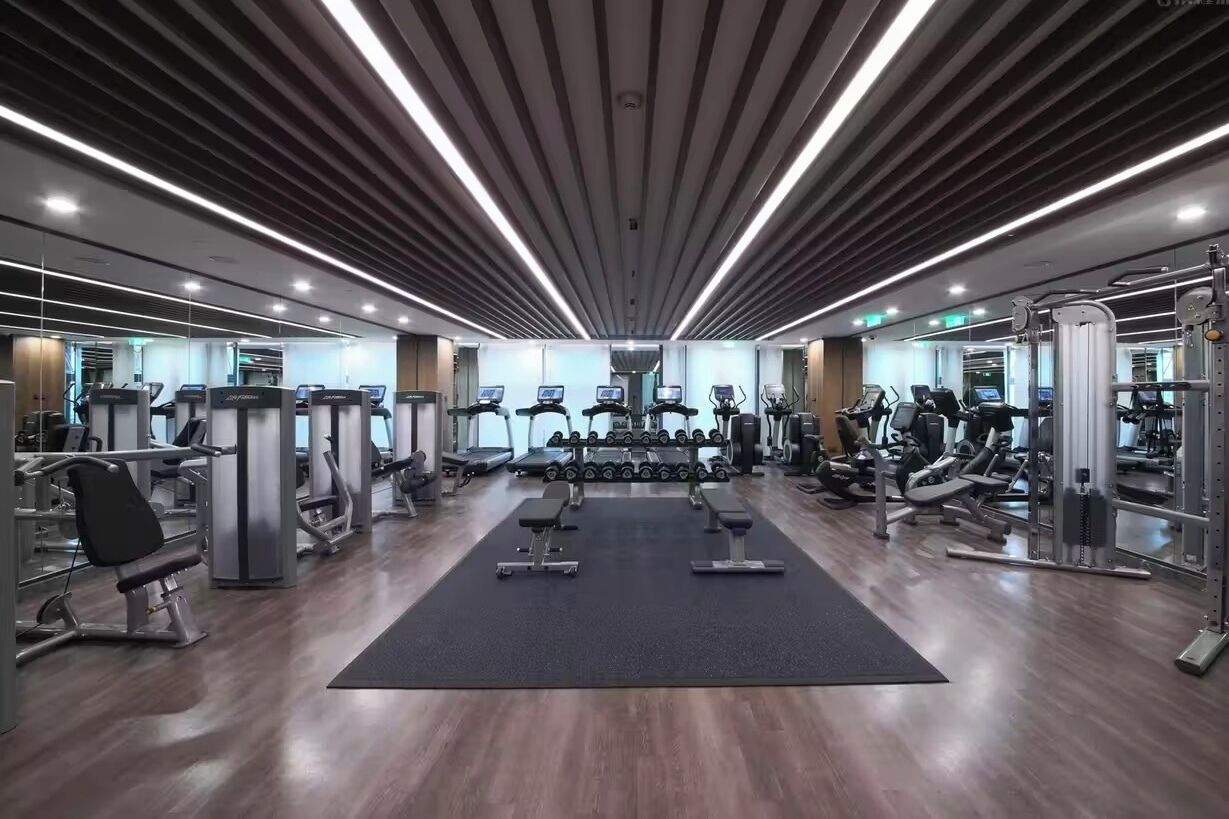 A modern gym with various exercise equipment, including treadmills, dumbbells, and weight machines.