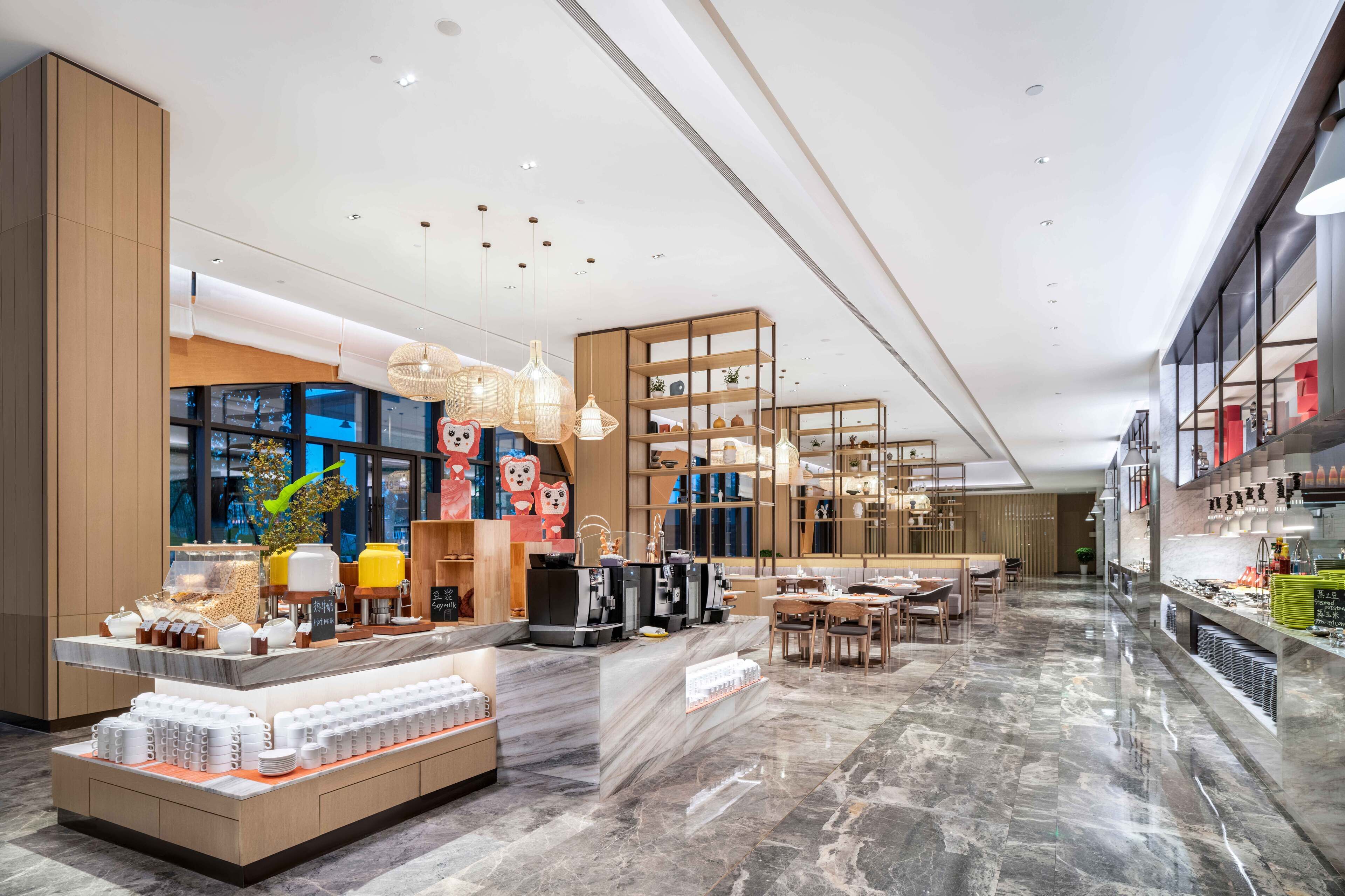 A modern cafe with a marble floor, wooden furniture, and a variety of coffee and tea displays.