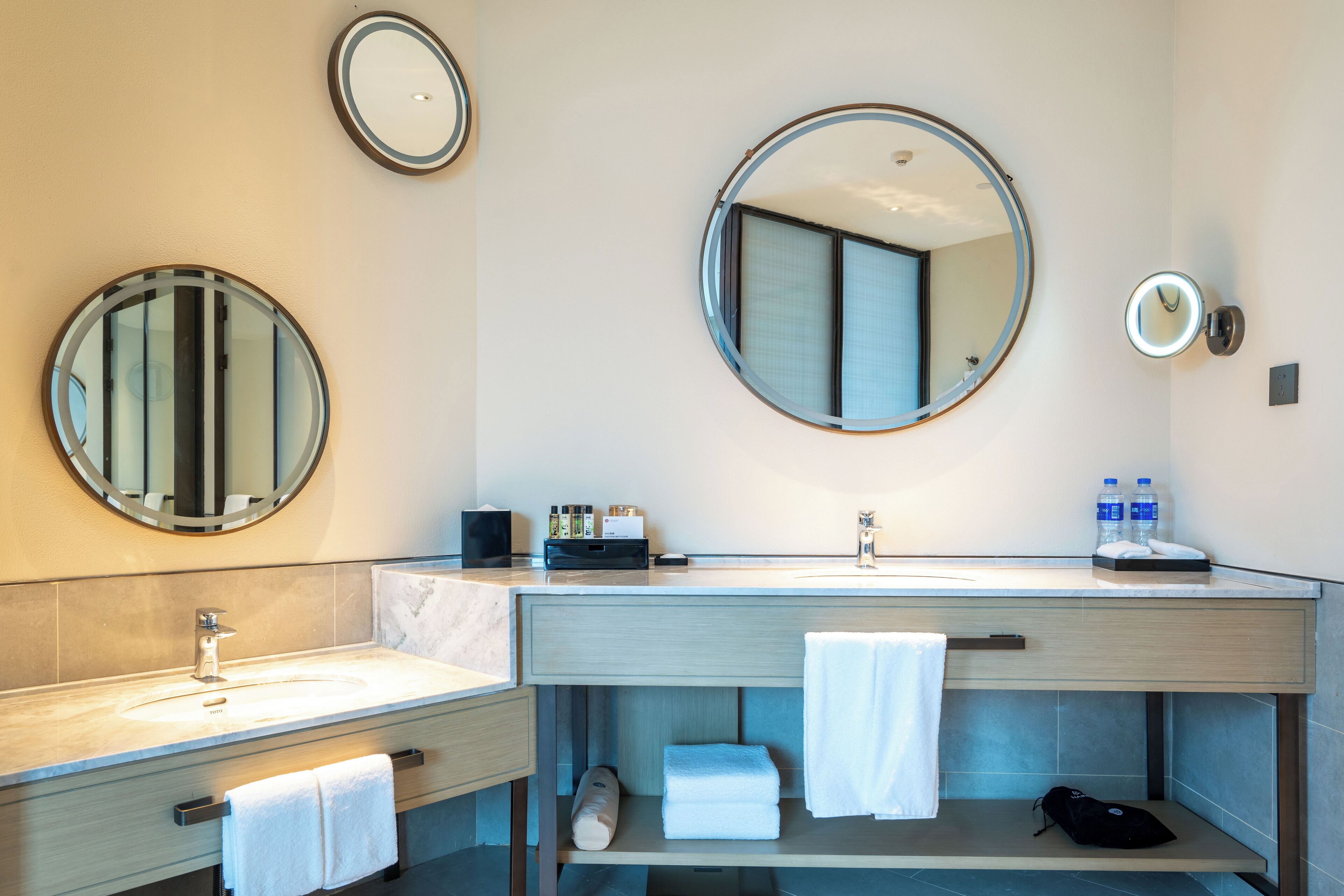 A modern bathroom with two sinks, a large mirror, and a towel rack.