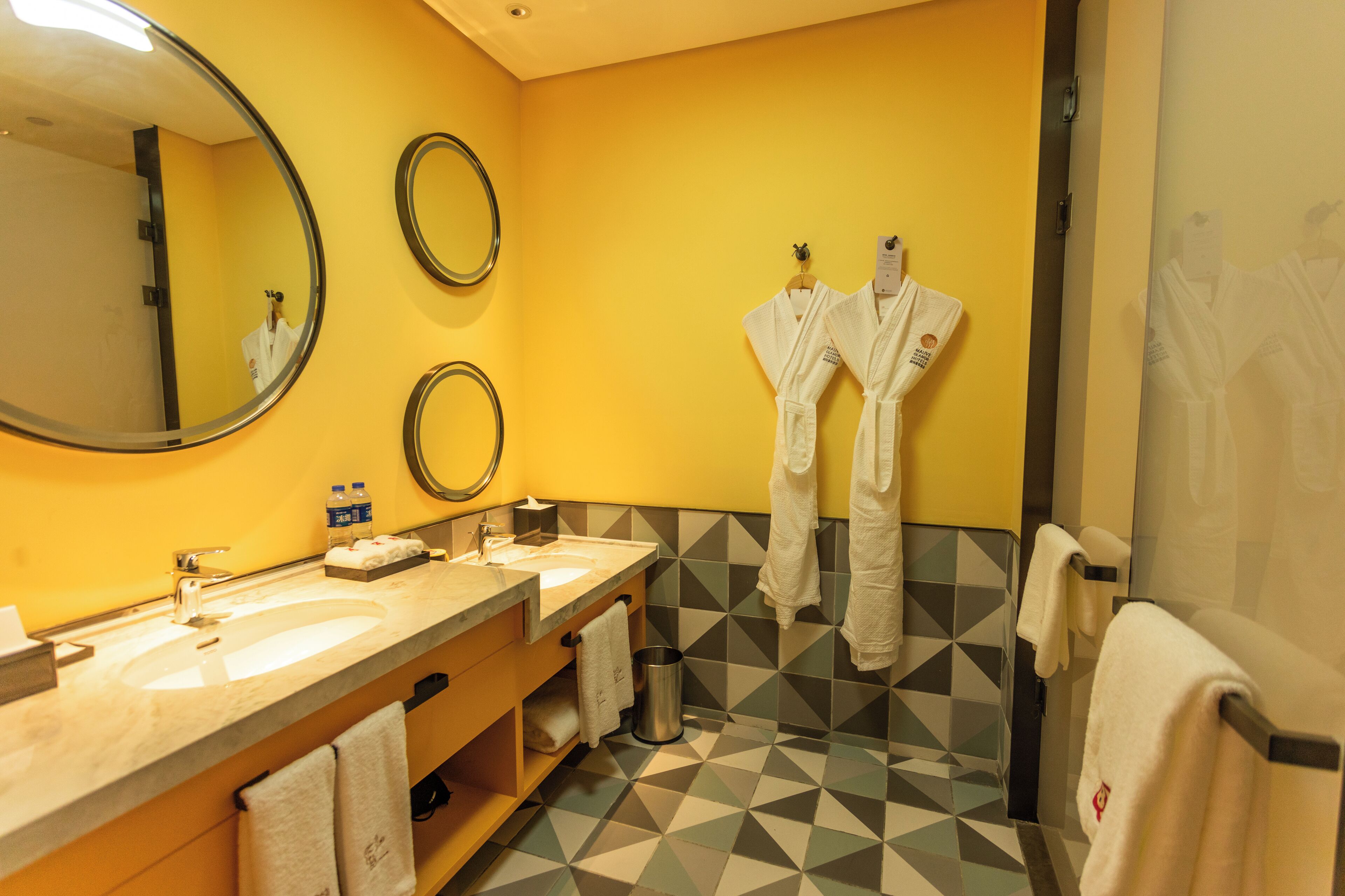 Un baño con dos lavamanos, un espejo y toallas colgadas en la pared.