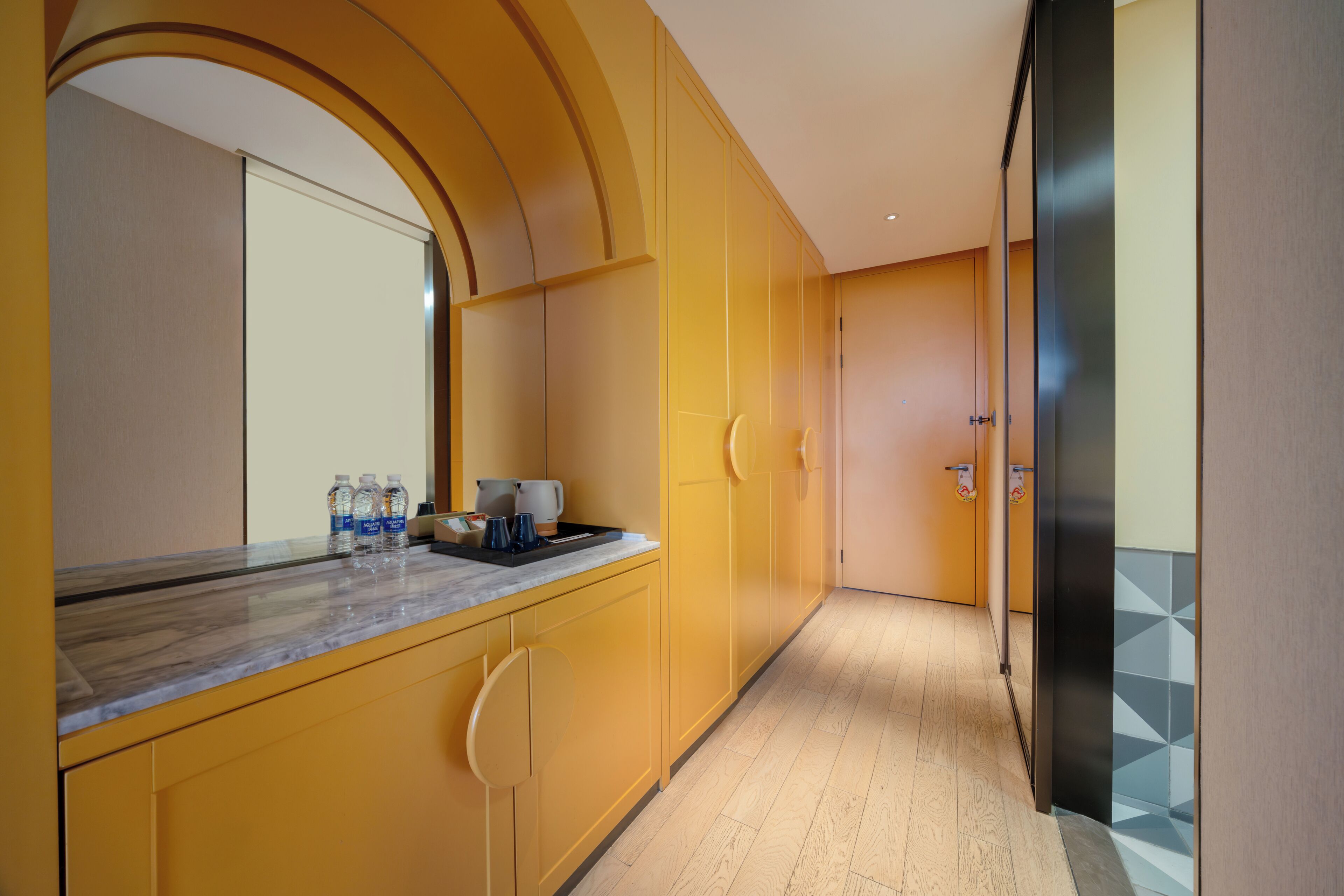 Una cocina moderna con gabinetes amarillos, una encimera de mármol y un espejo grande.