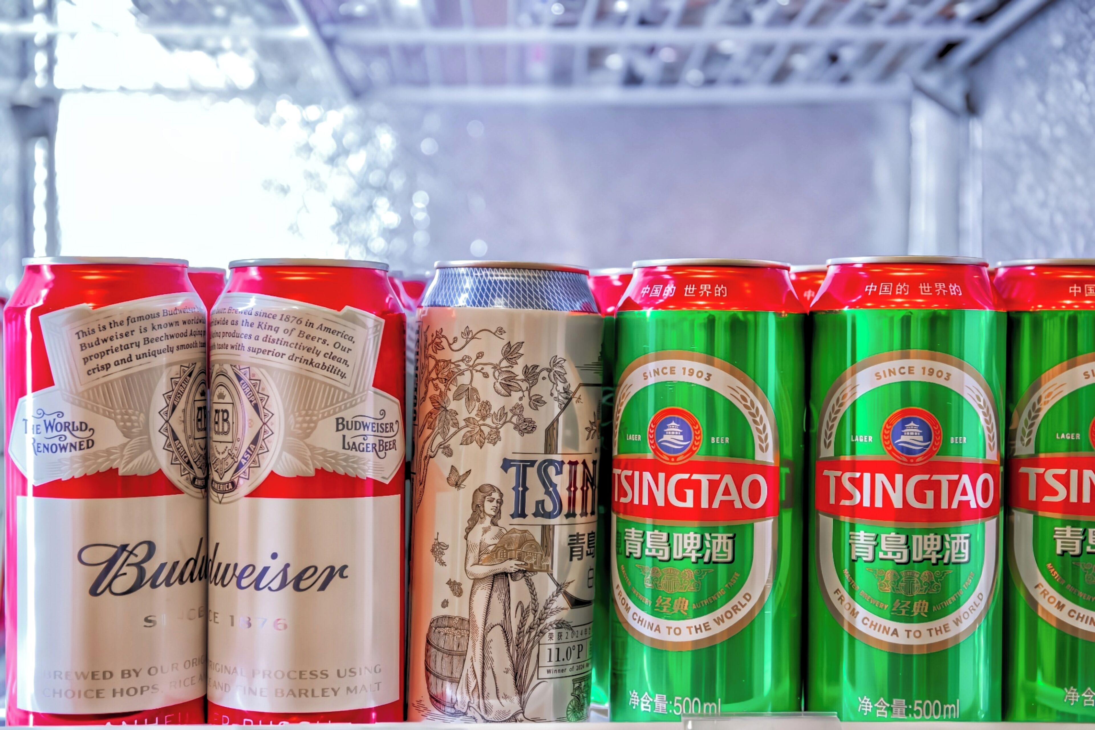 A row of beer cans on a shelf.