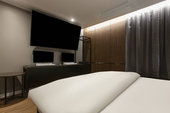 A modern hotel room with a large bed, a flat-screen TV mounted on the wall, a small table, and a wardrobe. - HOTEL GRAZIE (Goyang)