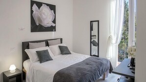 Une chambre à coucher avec un lit, une table de chevet, une lampe et un grand miroir.