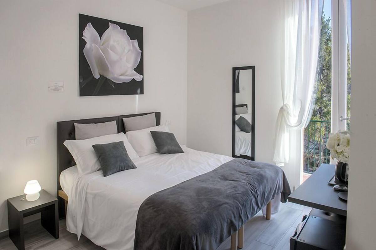 Ein Schlafzimmer mit Bett, Nachttisch, Lampe und einem großen Spiegel.
