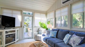 A living room with a TV, sofa, and a view of the outdoors.