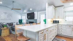 A modern kitchen with white cabinetry, a central island, and a dining area with a sofa and chairs.