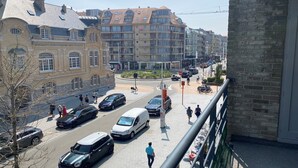 Une vue de rue avec un bâtiment présentant un style architectural classique, un rond-point et plusieurs voitures garées.