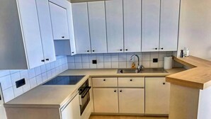 A compact kitchen with white cabinets, a built-in oven, and a sink. - Apartment near Port with Scenic Views (Nieuwpoort)