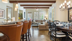 A spacious living area with a dining table, leather chairs, and a sofa. - Setting the Standard by AvantStay | Luxury Villa (La Quinta)