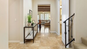 A hallway with a console table, a potted plant, and a staircase with a handrail. - Setting the Standard by AvantStay | Luxury Villa (La Quinta)