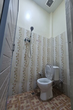A bathroom with a toilet, shower, and tiled walls. - Hotel O P&g Guest House (Medan)