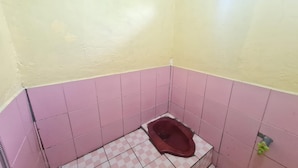 Um banheiro pequeno com azulejos rosa e brancos em xadrez, um vaso sanitário sanitário e uma janela.