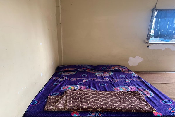 A small room with a single bed, a window with a blue curtain, and a wall with a visible patch. - Hotel O Pondok An Syariah (Bandung)