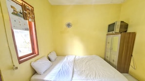 Quarto com cama, calendário, janela e televisão sobre um móvel.