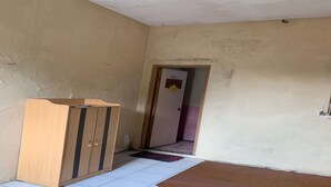 Um quarto com um armário de madeira, piso de azulejos e uma porta que dá para outro cômodo.