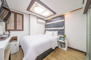 Una habitación de hotel moderna con cama, escritorio y un refrigerador pequeño.