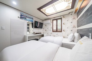 Habitación de hotel con dos camas, televisión, escritorio y ventana con vistas.