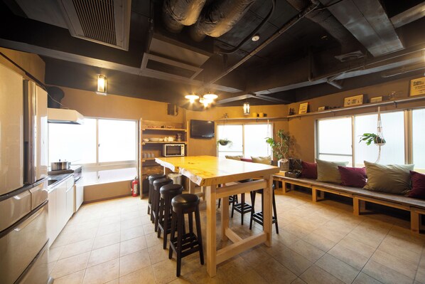 A kitchen with a wooden island, bar stools, a bench, and large windows. - Stay in Yokohama Retro Old Town, film and drama locations! 5LDK, 100 sq.m. 5-minute walk to JR Kannai Station and 6 stations on 4 lines are available! (横浜市中区吉田町)