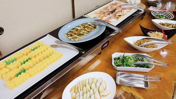 Une table de buffet proposant divers plats, notamment des omelettes, du poisson et des légumes.