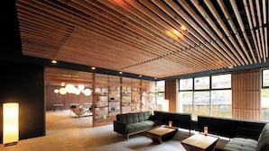 A modern interior with a wooden ceiling, a seating area with sofas and a coffee table, and a view through large windows.