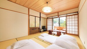A traditional Japanese room with tatami flooring, a low wooden ceiling, and sliding shoji doors.