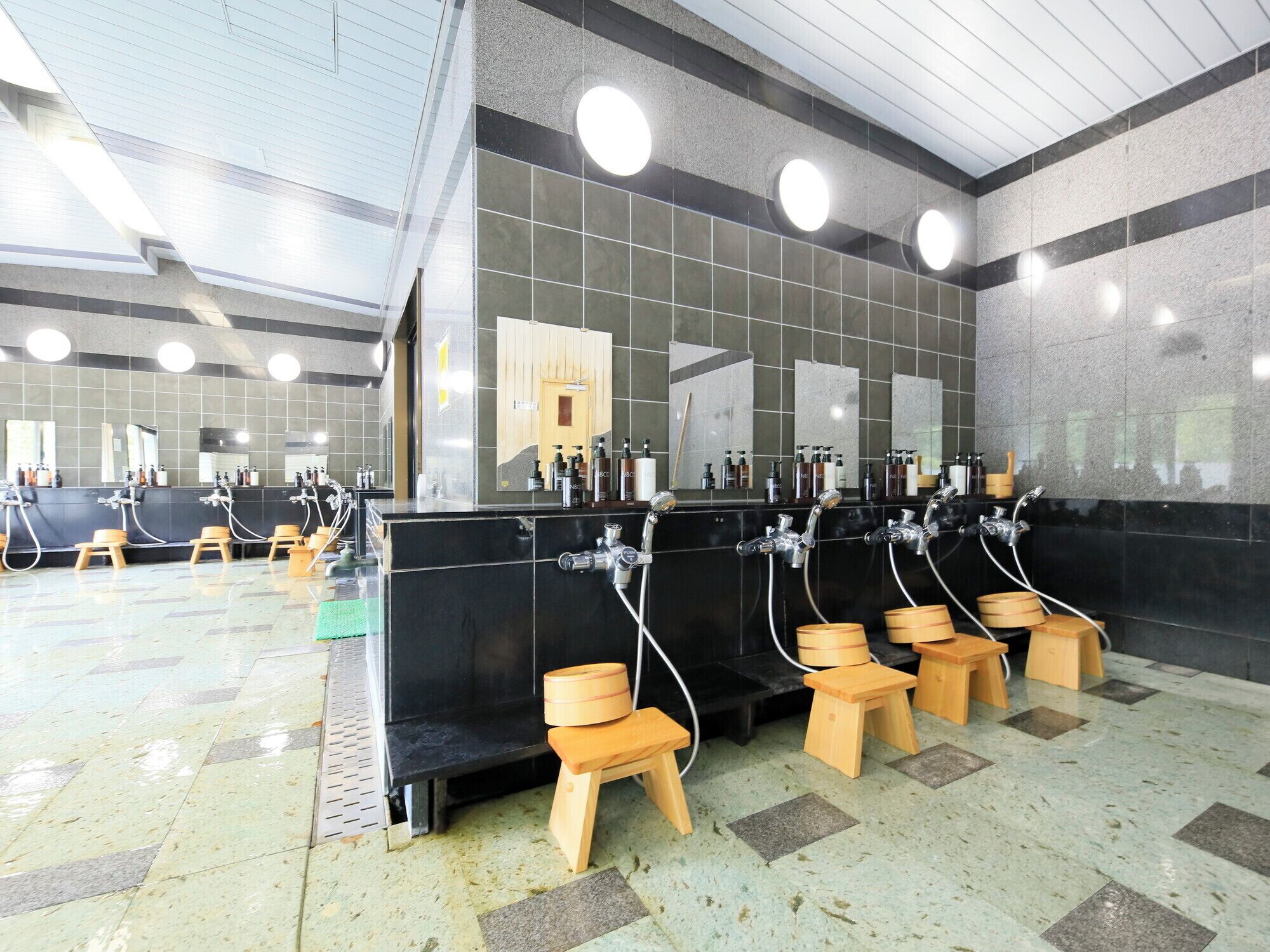 A public restroom with multiple sinks, mirrors, and wooden stools.